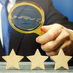 A man holds a magnifying glass over four stars. The evaluation of visitors.
